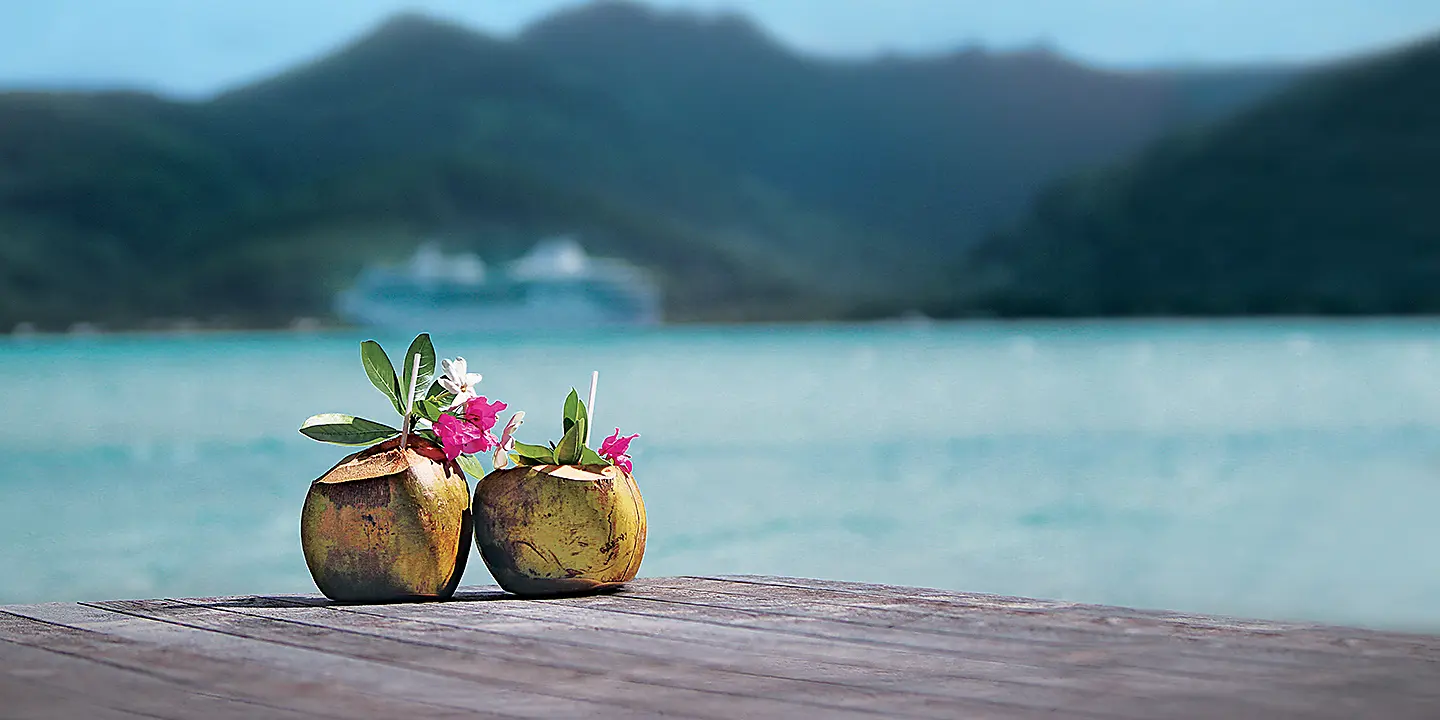 Paul Gauguin Cruises | Coconut drink with ship in background